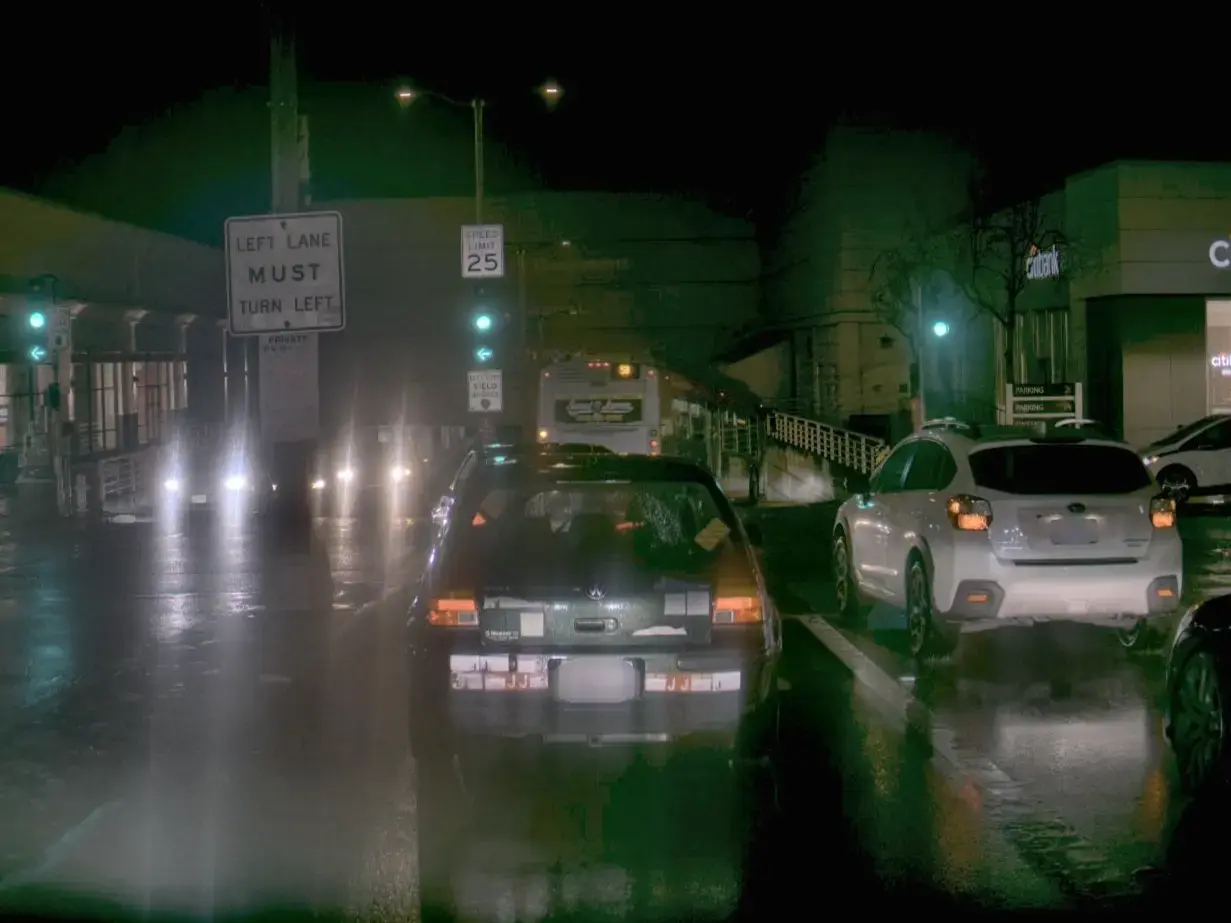 A picture of a dark street scene with a sign that says "left lane must turn left"
